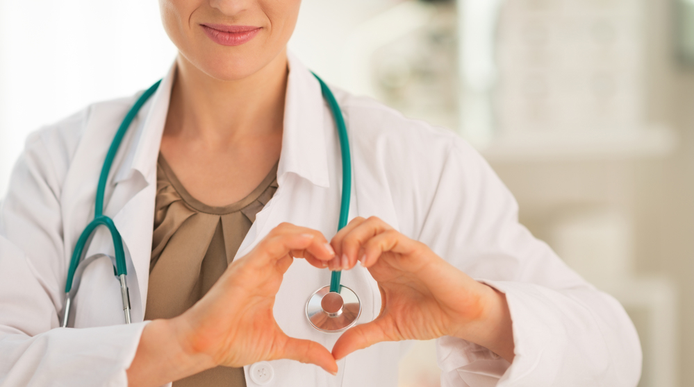 Closeup on female locum tenens showing heart shape gesture with hands.