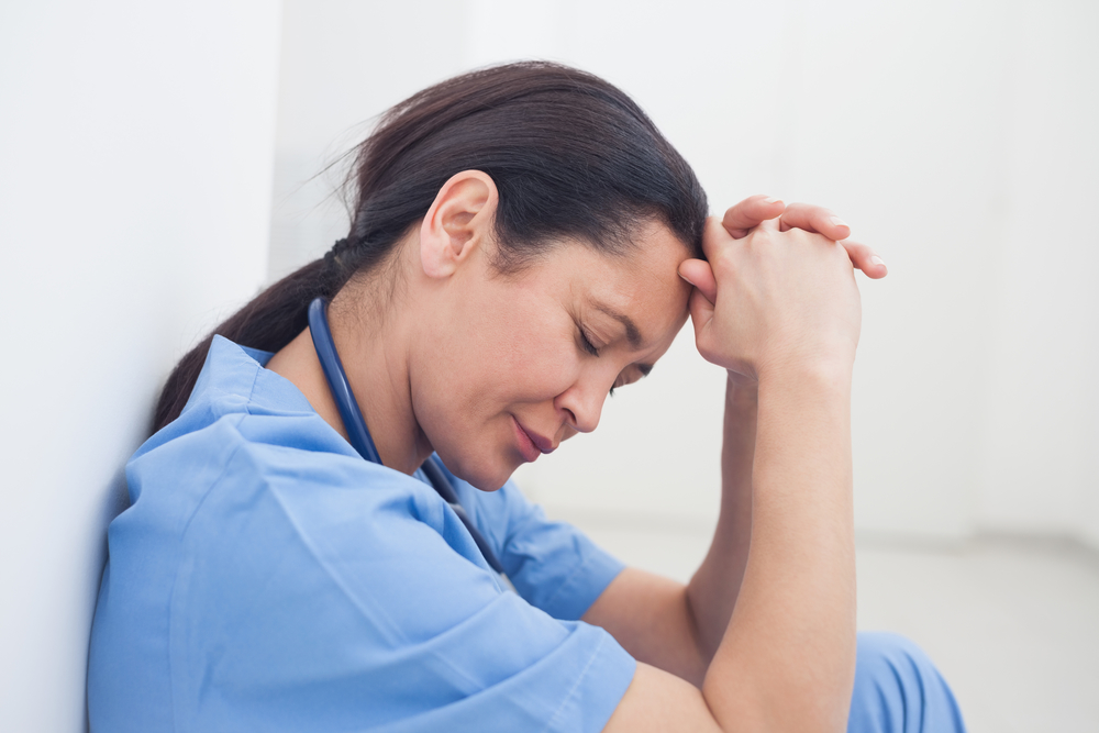 Upset nurse sitting on the floor in hospital ward to show physician burnout